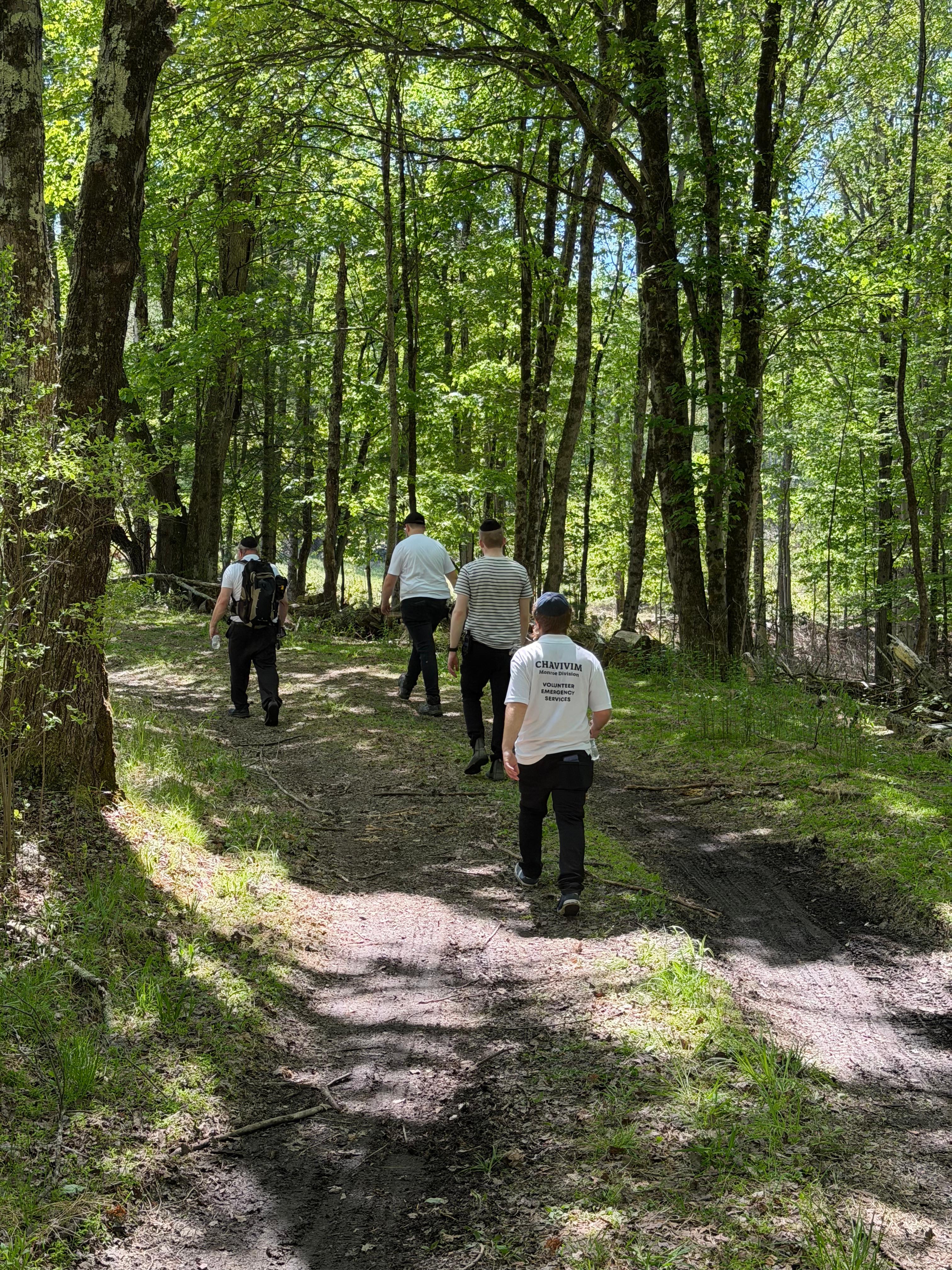 Chavivim members in single-file formation walking a wooded path during a SAR training exercise