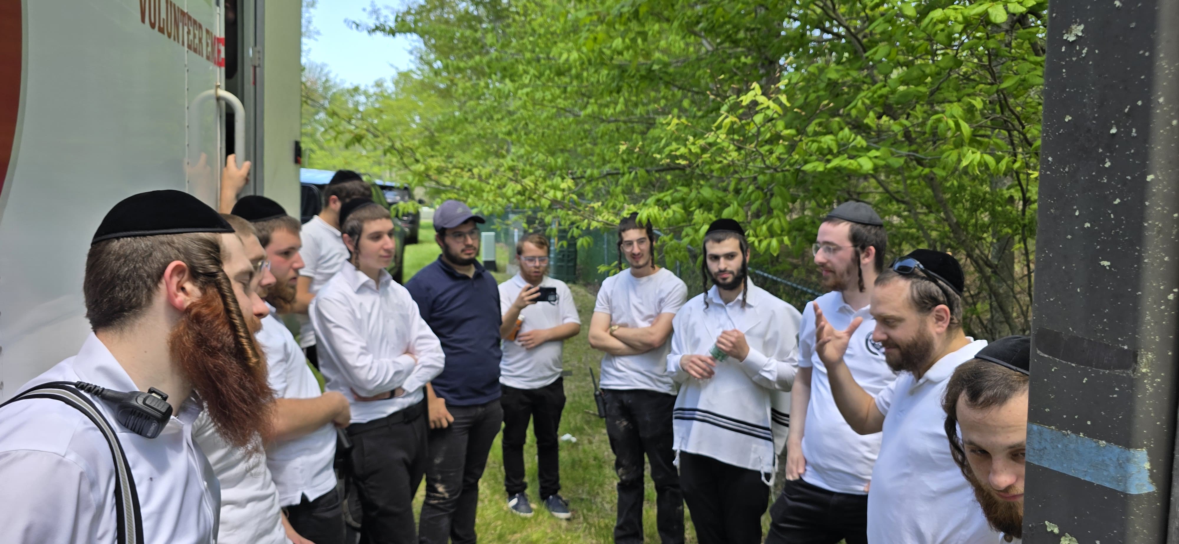 Chavivim members gathered around a leader at the side of the KJ-500 Command Center truck for pre-mission instructions