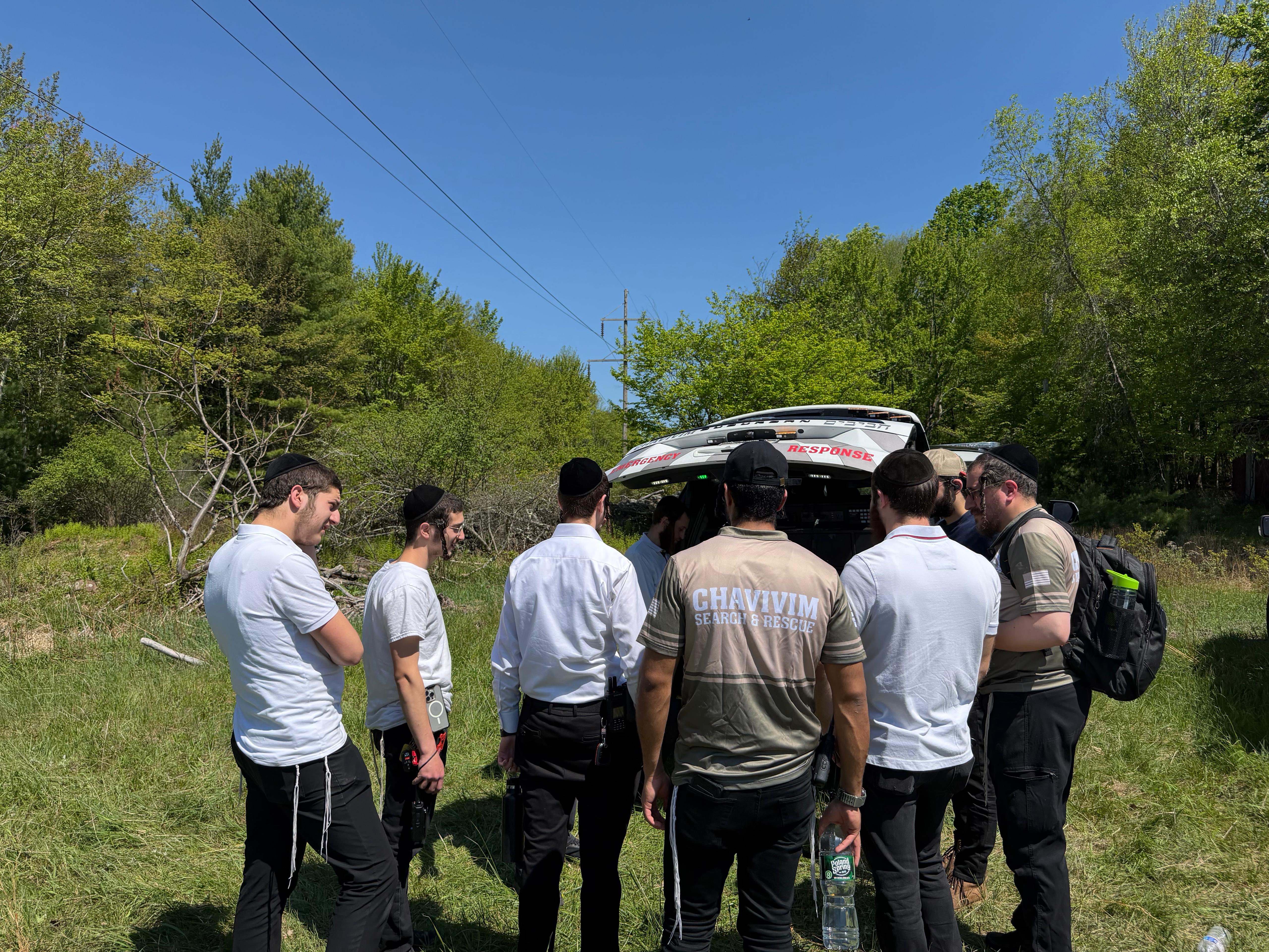 Chavivim SAR-shirted team gathered at the back of the KJ-500 Command Center with response gear staged