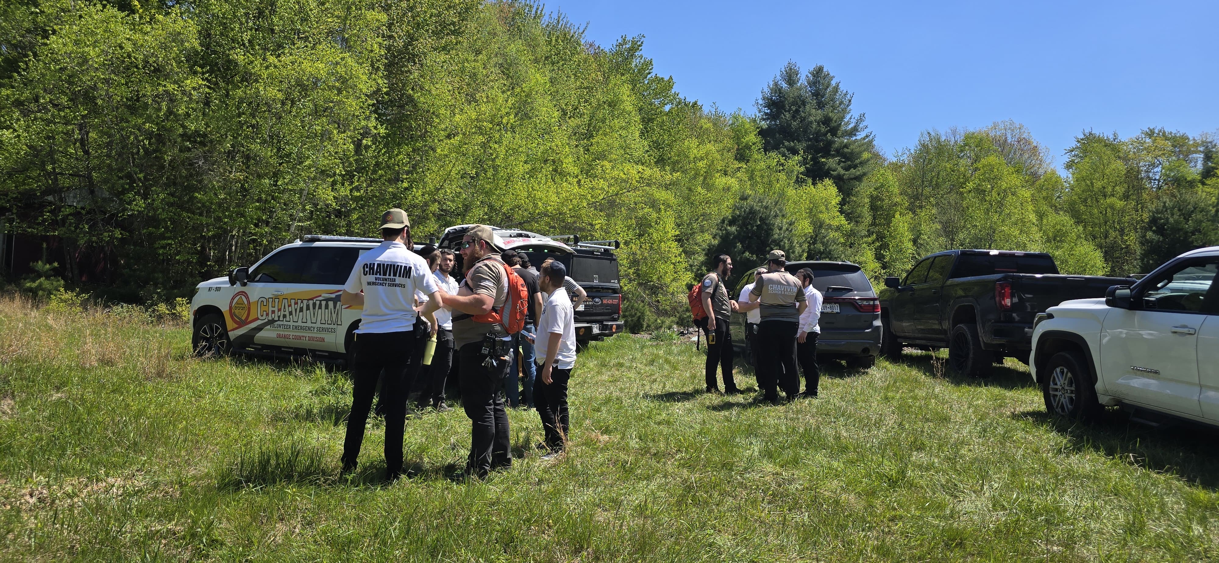 Wide view of the Chavivim SAR training staging area with response and crew vehicles in a Catskills clearing